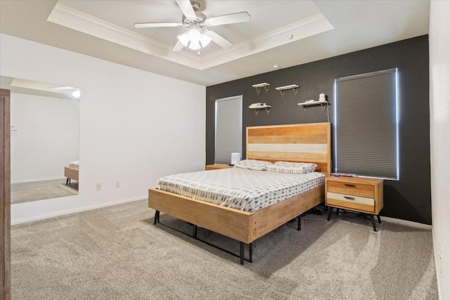 carpeted bedroom with a raised ceiling, ceiling fan, and crown molding