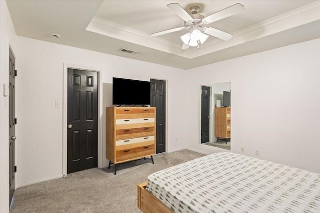 carpeted bedroom featuring a raised ceiling, ceiling fan, and ornamental molding