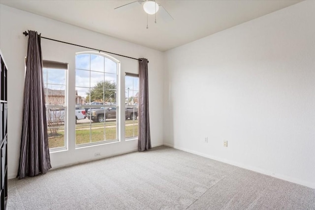 carpeted spare room featuring a wealth of natural light and ceiling fan