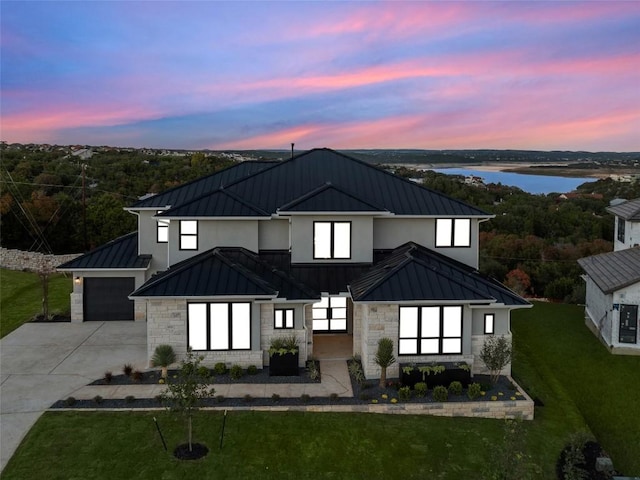 exterior space with a water view, a garage, and a lawn