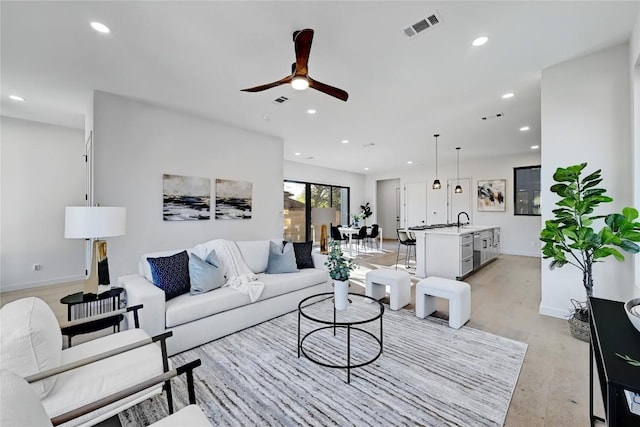 living room with light hardwood / wood-style flooring, ceiling fan, and sink