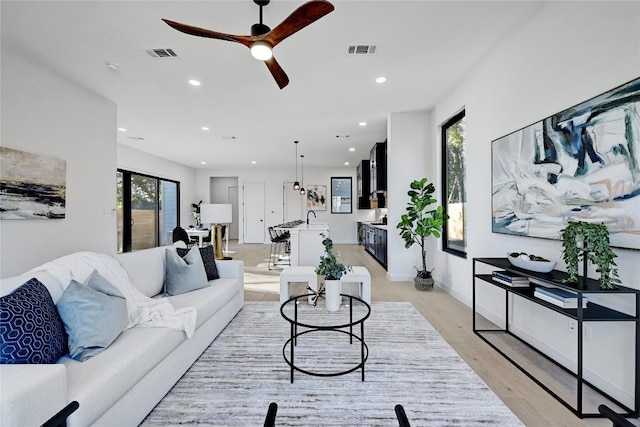 living room with a wealth of natural light, light hardwood / wood-style floors, and ceiling fan