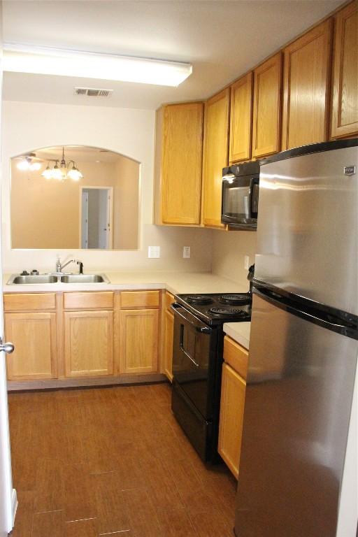 kitchen with a chandelier, sink, dark hardwood / wood-style floors, and black appliances