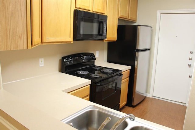 kitchen featuring sink, light brown cabinetry, black appliances, and wood-type flooring