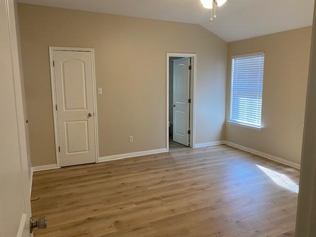 unfurnished bedroom with light hardwood / wood-style floors and lofted ceiling