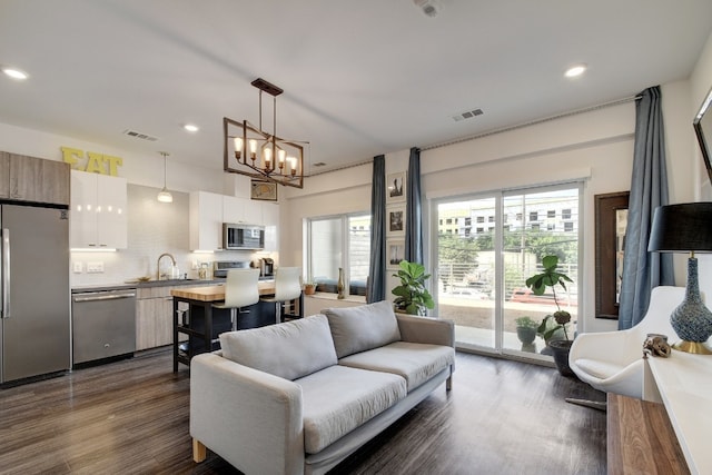 living room featuring dark hardwood / wood-style flooring, sink, and a chandelier