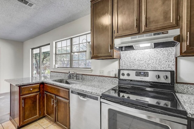 kitchen with light stone countertops, sink, stainless steel appliances, a textured ceiling, and light tile patterned flooring