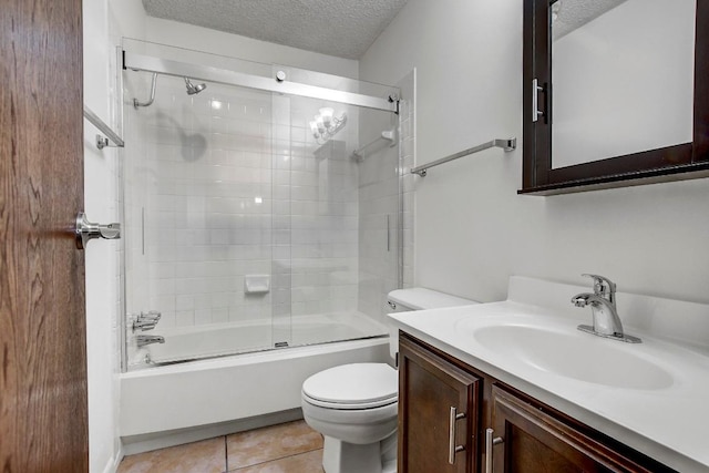 full bathroom featuring vanity, tile patterned floors, bath / shower combo with glass door, toilet, and a textured ceiling