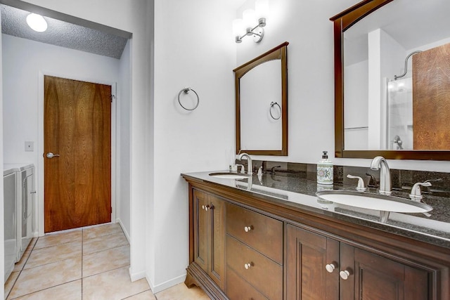 bathroom featuring tile patterned flooring, vanity, washer and dryer, and a textured ceiling