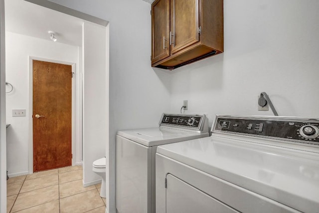 laundry area with light tile patterned flooring, cabinets, and washing machine and clothes dryer