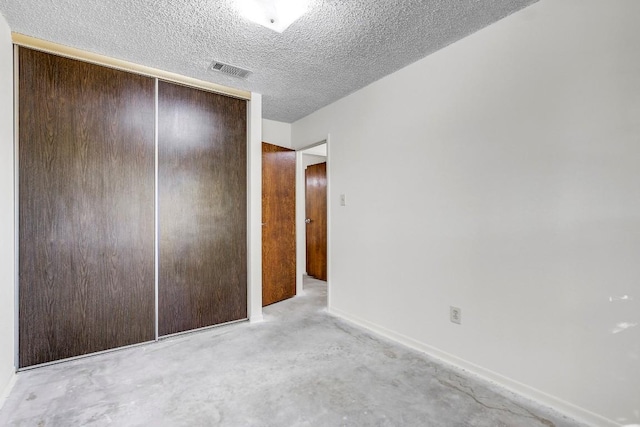 unfurnished bedroom featuring a textured ceiling and a closet