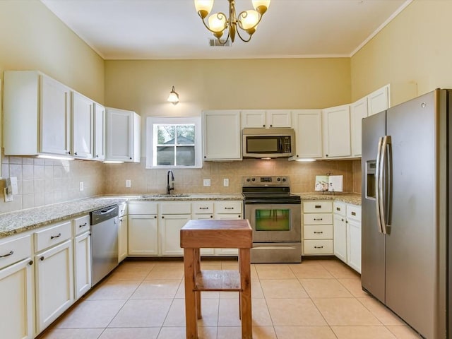 kitchen with white cabinetry, stainless steel appliances, light stone counters, a chandelier, and light tile patterned floors