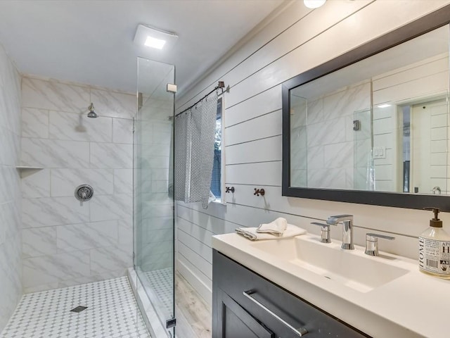 bathroom featuring tiled shower, vanity, and wooden walls