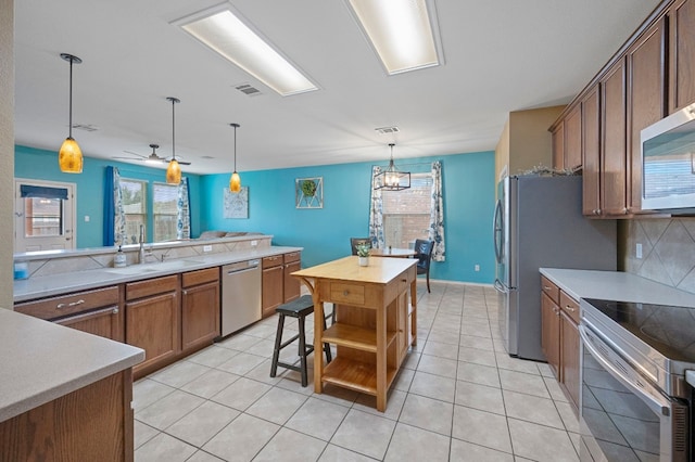 kitchen featuring hanging light fixtures, decorative backsplash, sink, a kitchen island, and stainless steel appliances