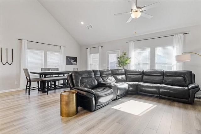 living room with light hardwood / wood-style floors, high vaulted ceiling, and ceiling fan