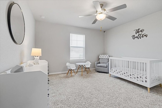 bedroom featuring ceiling fan, a crib, and carpet floors