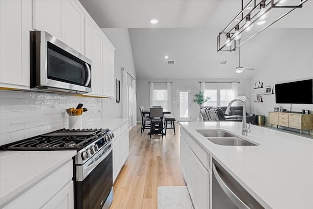 kitchen featuring white cabinetry, sink, appliances with stainless steel finishes, and vaulted ceiling