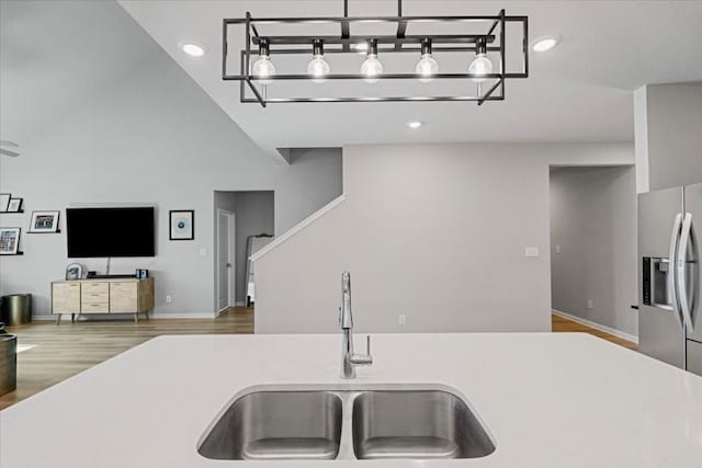 kitchen featuring hardwood / wood-style floors, stainless steel fridge with ice dispenser, sink, and high vaulted ceiling