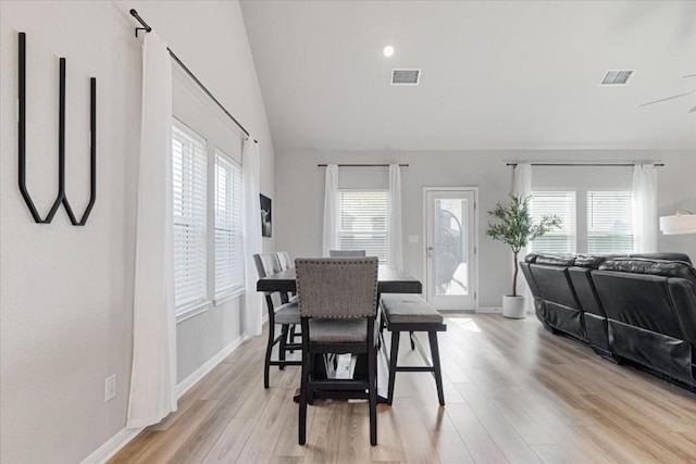 dining room featuring light wood-type flooring, vaulted ceiling, and plenty of natural light