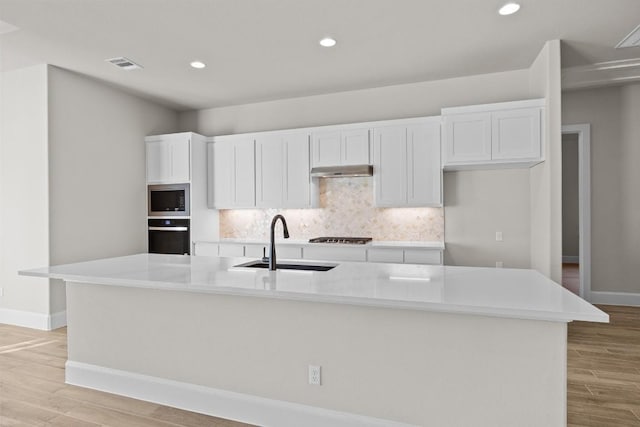 kitchen with white cabinets, a spacious island, sink, and light hardwood / wood-style flooring