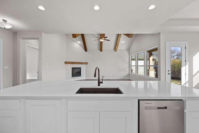 kitchen featuring vaulted ceiling with beams, dishwasher, white cabinets, and sink