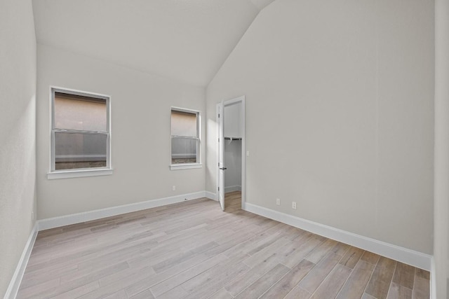 spare room featuring light wood-type flooring and vaulted ceiling