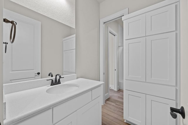 bathroom with hardwood / wood-style flooring, vanity, and a textured ceiling