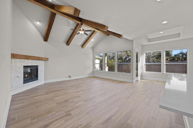 unfurnished living room featuring ceiling fan, a healthy amount of sunlight, high vaulted ceiling, and light hardwood / wood-style flooring