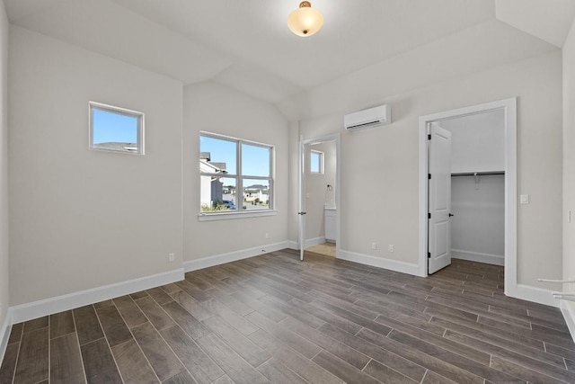 unfurnished bedroom featuring a wall mounted air conditioner, lofted ceiling, dark wood-type flooring, a spacious closet, and a closet