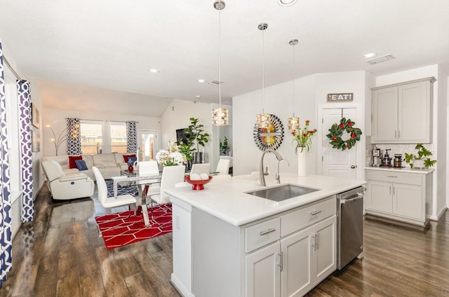 kitchen with light countertops, hanging light fixtures, stainless steel dishwasher, a sink, and an island with sink