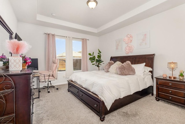 bedroom featuring baseboards, a tray ceiling, and light colored carpet