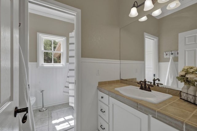 bathroom with toilet, vanity, tile patterned floors, and ornamental molding