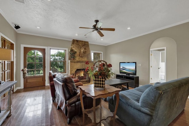 living room with a fireplace, hardwood / wood-style floors, a textured ceiling, and ornamental molding