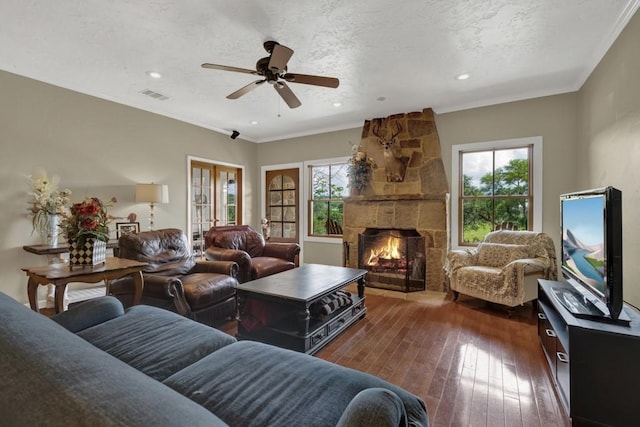 living room featuring ornamental molding, a stone fireplace, plenty of natural light, and dark wood-type flooring