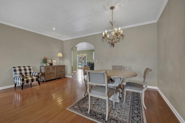 dining space featuring hardwood / wood-style floors, crown molding, and a chandelier