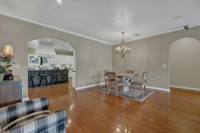 dining space with a chandelier, hardwood / wood-style flooring, and crown molding