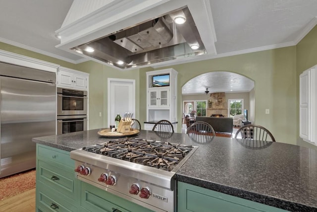 kitchen with appliances with stainless steel finishes, ornamental molding, custom range hood, green cabinetry, and white cabinetry