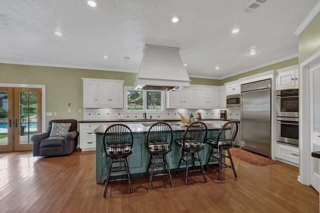 kitchen featuring white cabinets, built in appliances, and a wealth of natural light