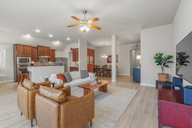 living room with ceiling fan with notable chandelier and light hardwood / wood-style flooring