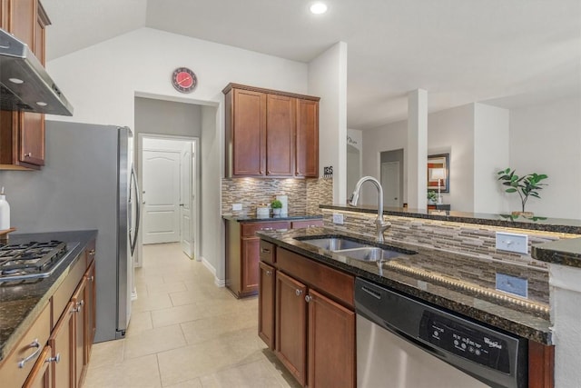 kitchen featuring sink, backsplash, dark stone counters, light tile patterned flooring, and appliances with stainless steel finishes