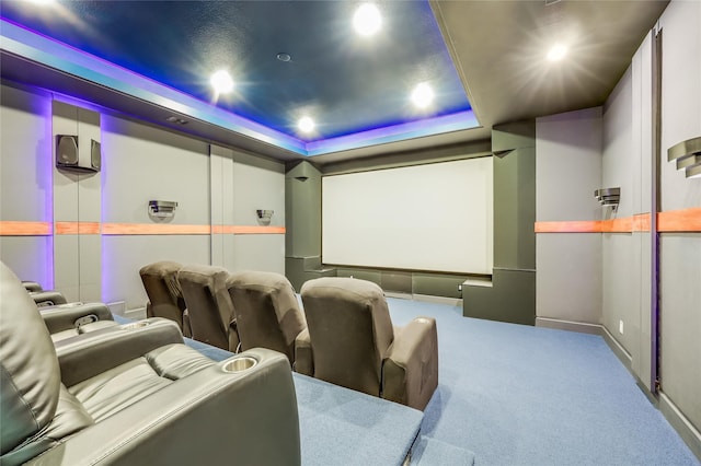 carpeted home theater room with a raised ceiling