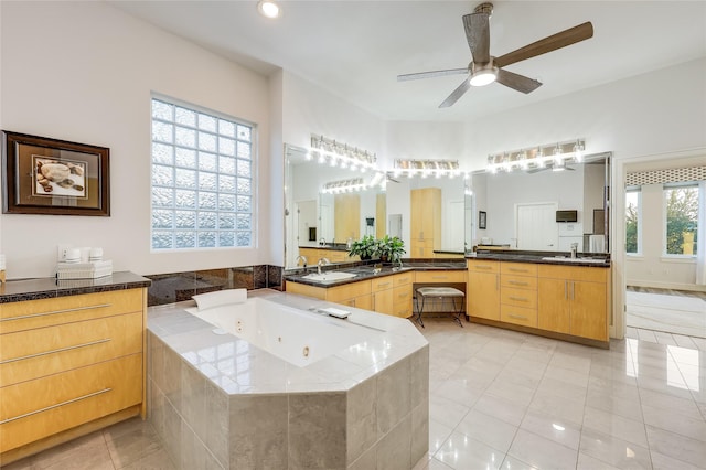 bathroom with tiled tub, tile patterned floors, ceiling fan, and a healthy amount of sunlight