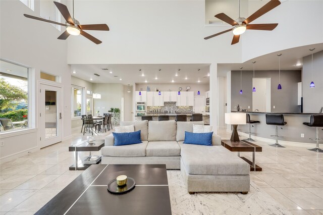 living room featuring a high ceiling, ceiling fan, and light tile patterned floors