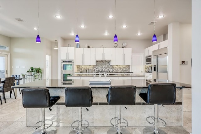 7302 Matisse Pointe Dr, Jonestown, TX 78645 - kitchen with built in appliances, white cabinetry, decorative backsplash, a large island with sink, and hanging light fixtures