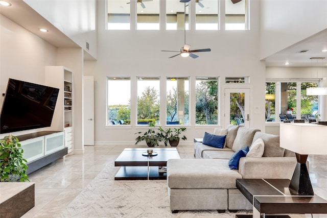 living room featuring a high ceiling, ceiling fan, and a wealth of natural light