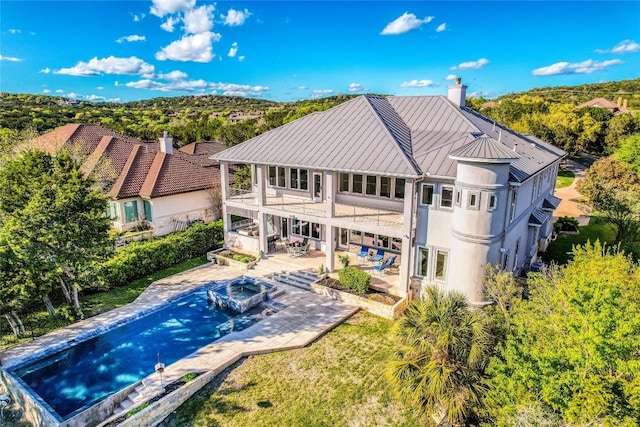 7302 Matisse Pointe Dr, Jonestown, TX 78645 - back of property featuring a balcony, a chimney, stucco siding, a standing seam roof, and a patio