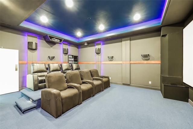 cinema room with a raised ceiling and carpet flooring