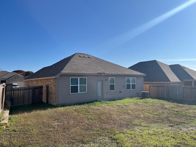 back of property with central AC and a lawn
