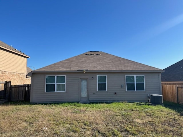 back of house with central air condition unit and a lawn