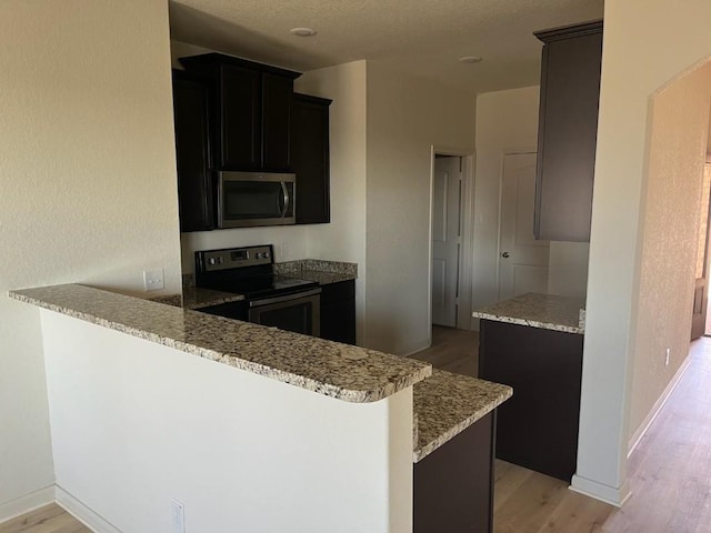 kitchen with kitchen peninsula, light hardwood / wood-style floors, and range with electric stovetop